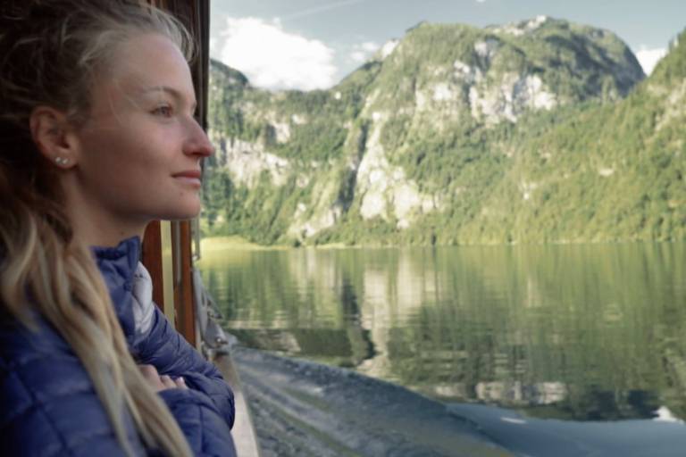 Eine junge Frau betrachtet den Königssee vom Schiff aus